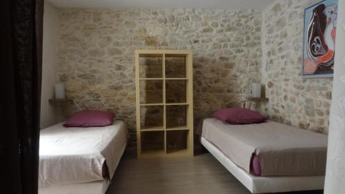 two beds in a room with brick walls at Appartement avec patio,2 chambres,Patangarles in Arles