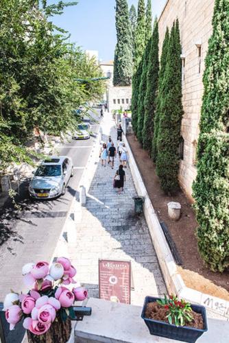 a group of people walking down a street with pink flowers at La Casetta in Nazareth