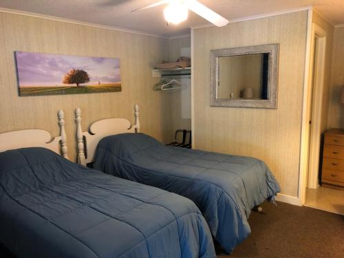 a bedroom with two beds and a mirror at West Winds Motel & Cottages in Clayton