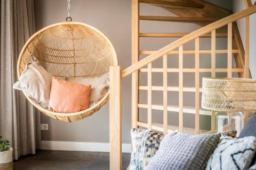 デン・ブルグにあるJust Texel Suites & Apartmentsの二段ベッド付きのベッドルームに籐の吊りバスケット
