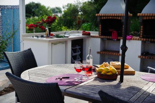 Una mesa con dos copas de vino y un bol de fruta. en Casa Verdazul, en Tavira