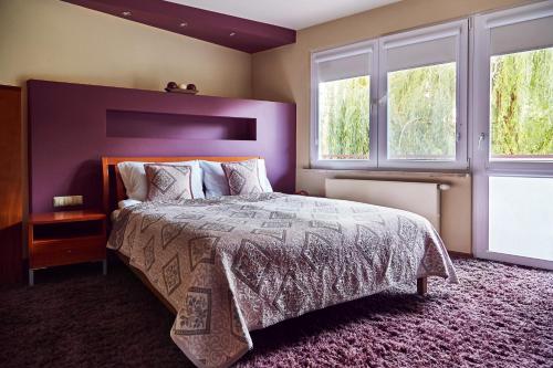 a bedroom with a large bed and two windows at Apartament Królewski in Sandomierz