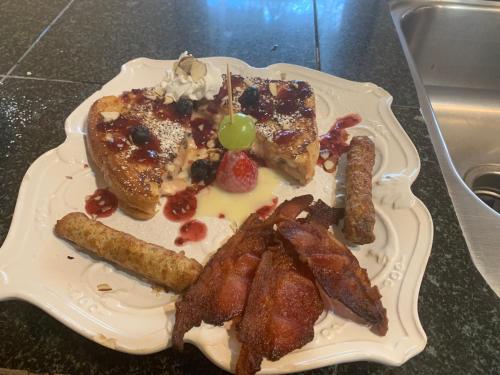 a plate of breakfast food with bacon and french toast at Peace & Plenty Inn Bed and Breakfast Downtown St Augustine-Adults Only in Saint Augustine