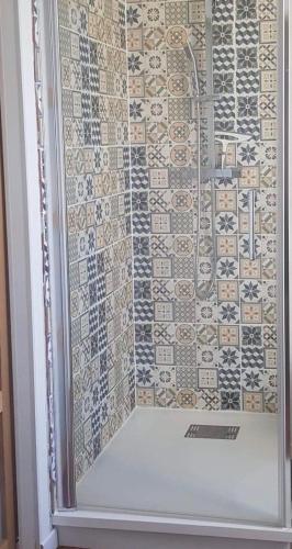 une douche avec une porte vitrée et un mur carrelé dans l'établissement Carré Saint-Gervais Rouen centre, à Rouen