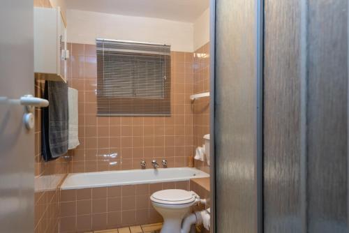 ein Badezimmer mit einem WC und einer Badewanne in der Unterkunft Pebble Beach 13 in Ballito