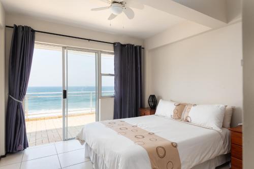 a bedroom with a bed and a view of the ocean at Pebble Beach 13 in Ballito