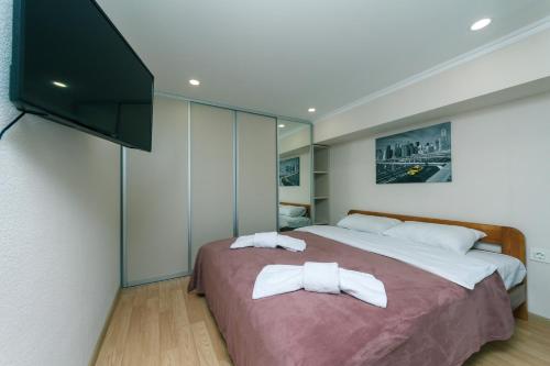 a bedroom with a large bed and a flat screen tv at My SmartApart Hotel Today in Kyiv