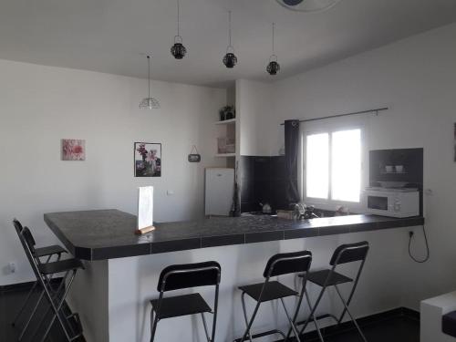 a kitchen with a counter with four bar stools at African Jaja villa Piscine-Climatisation in Poponguine