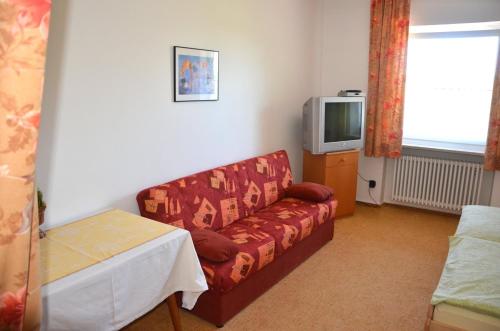 a living room with a couch and a tv at Landgasthof zur Quelle in Seeshaupt