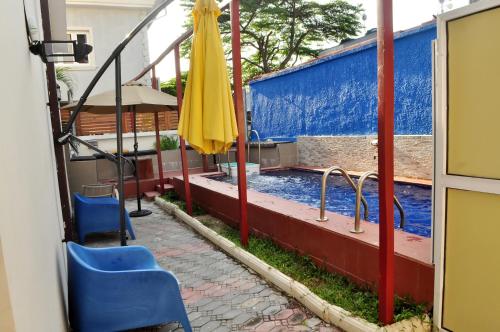 a swimming pool with two chairs and an umbrella at J Gibson Hotel in Lagos