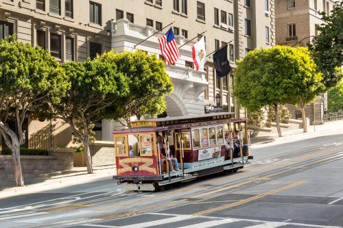 a trolley car driving down a city street with american flags at Stanford Court San Francisco in San Francisco