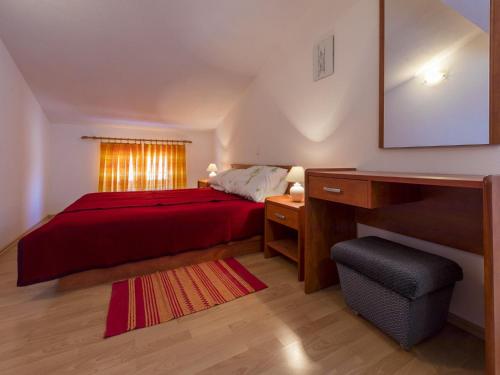 a bedroom with a red bed and a desk and a window at Apartments Maro in Dramalj