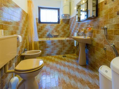 a bathroom with two toilets and a sink and a tub at Apartment Agava in Bribir