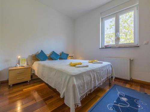 - une chambre avec un lit doté d'oreillers bleus et d'une fenêtre dans l'établissement Apartment Helena, à Dramalj