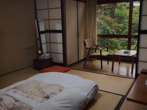 a bedroom with a bed and a balcony with a chair at Ishiba Ryokan in Hirosaki