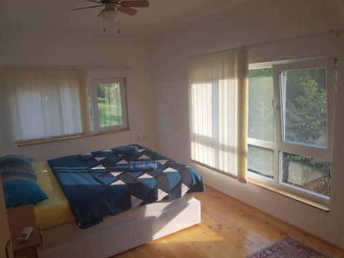 a bedroom with a bed and two windows at Sam guest house in Jajce