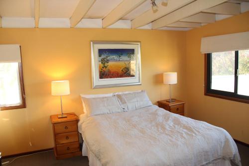 a bedroom with a white bed and two lamps at Gabbadah Beach House in Guilderton