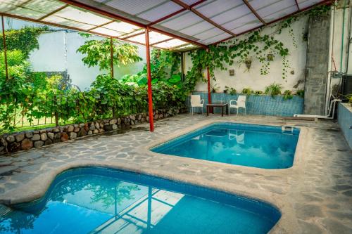 een zwembad met een pergola naast een huis bij Hotel Vitorina in Atlixco
