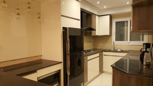 a kitchen with a black refrigerator and white cabinets at Sheraton Ocean 401 - No Pool Access in Cairo