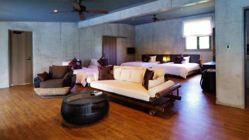 a large room with two beds and a couch and chairs at Magachabaru Okinawa in Nakijin