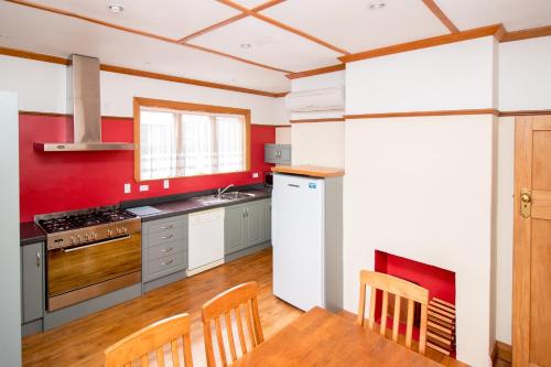 a kitchen with red and white walls and a table and chairs at Langdale Lodge in Kurow