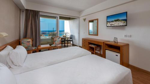 a hotel room with two beds and a desk at Sirene Beach Hotel in Ixia