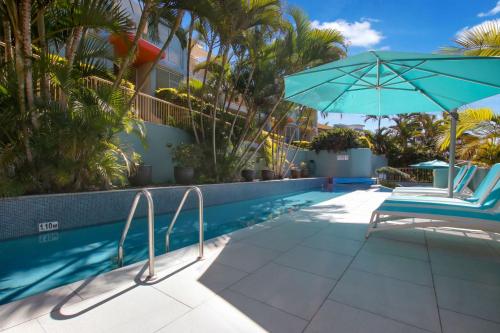 a swimming pool with a chair and an umbrella at Lennox Beach Resort in Lennox Head