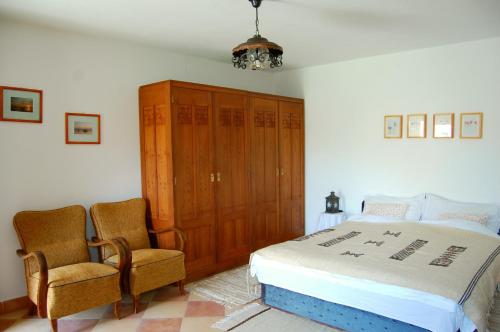 a bedroom with a bed and two chairs at Nohab Apartman in Badacsonytördemic