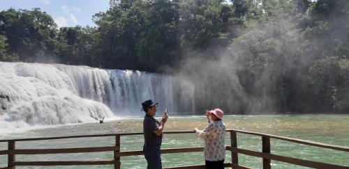 a man and woman standing in front of a waterfall at Cabañas Yax-ha in Arroyo Agua Azul