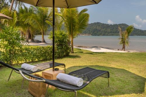 two chairs and an umbrella on a beach at Peninsula Beach Resort in Ko Chang