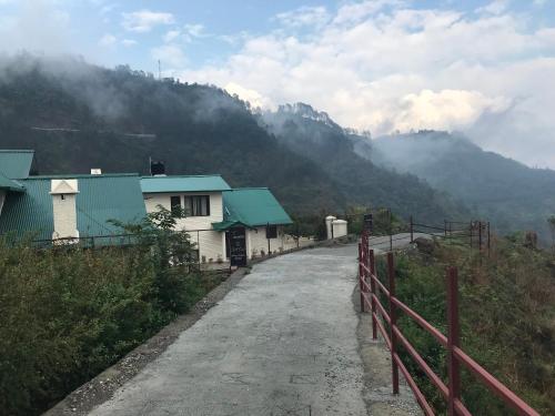 a road leading to a house with mountains in the background at Karinya Villas in Nainital