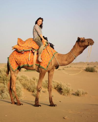 a woman riding on a camel in the desert at Sunny Desert Camp in Kūri