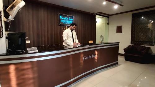 a man standing at a counter in a hotel lobby at Fiesta Inn Hotel & Resorts Multan in Multan