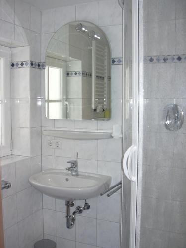 a white bathroom with a sink and a mirror at Pension Herzoghäusel in Bischofswiesen