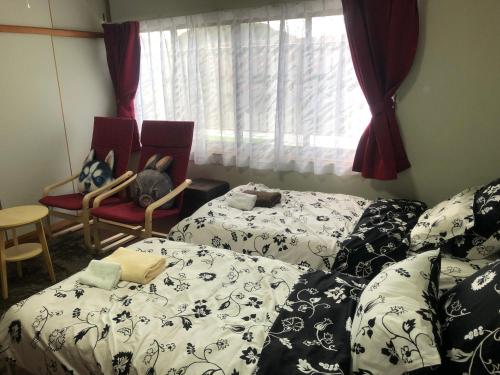 a room with two beds and chairs and a window at Guesthouse Yui in Hongu