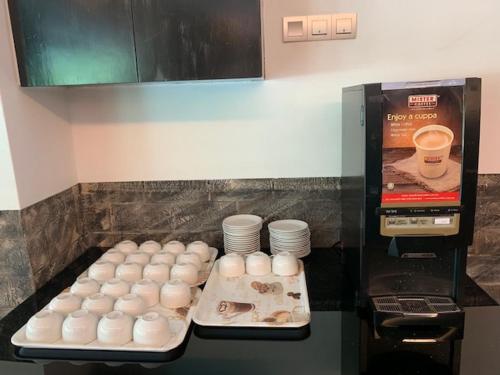 a counter with a bunch of cups and plates at 7 Heaven Boutique Hotel in Pasir Gudang
