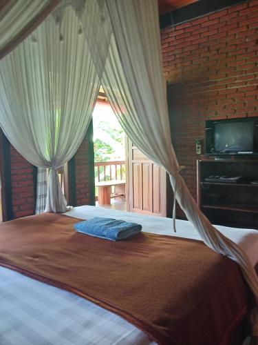 a bedroom with a bed with curtains and a television at Pondok Balian in Selemadeg