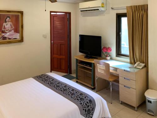 a bedroom with a desk with a bed and a television at The Classroom Hotel in Pattaya