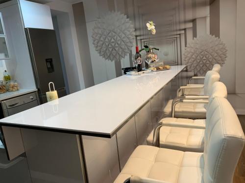 a kitchen with a white counter and a row of chairs at Céntrico ,Moderno y confortable Apartament in Almería
