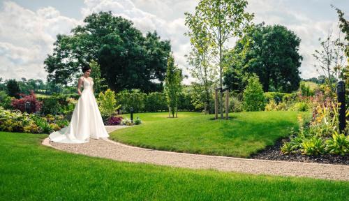 a bride walking down a path in a garden at Cavan Crystal Hotel in Cavan