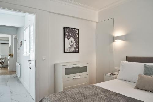 a white bedroom with a bed and a tv at Marvelous n Bright Apt next to Megaro Mousikis in Athens
