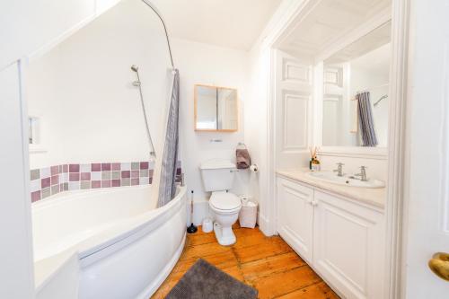 a bathroom with a tub and a toilet and a sink at Elegant Period Clifton Balcony Apt - Simply Check In in Bristol