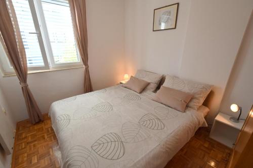 um quarto com uma cama com lençóis brancos e almofadas em Apartment Buza em Malinska