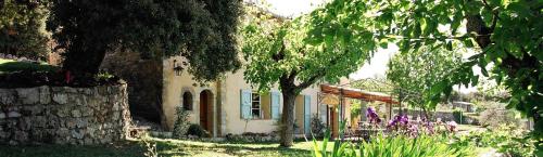 une maison blanche avec un mur en pierre et des arbres dans l'établissement Roubies, à Mons