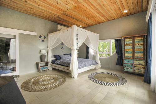 Coco Verde Bali Resort في تاناه لوت: غرفة نوم بسرير مع مظلة