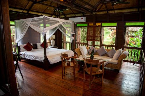 a bedroom with a bed and a couch and a table at Sunset Valley Holiday Houses in Kampung Padang Masirat