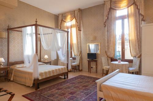 a bedroom with two beds and a television and windows at Dimora Al Doge Beato vista canale in Venice