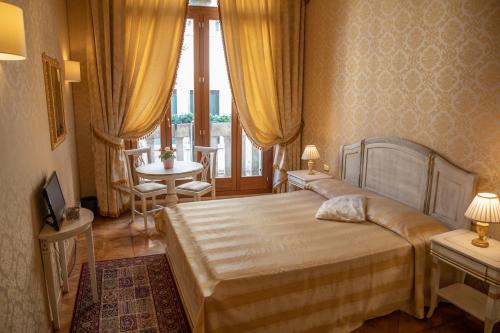 a bedroom with a bed and a table and a window at Dimora Al Doge Beato vista canale in Venice
