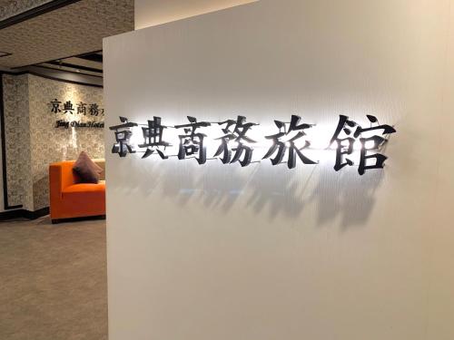 a wall with a sign on it next to a orange couch at Jing Dian Business Hotel in Taoyuan