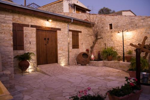 a stone house with a wooden door and a courtyard at Xenios Cottages in Lofou
